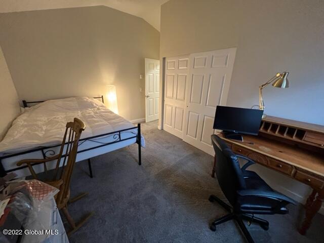 bedroom with lofted ceiling, a closet, and carpet floors