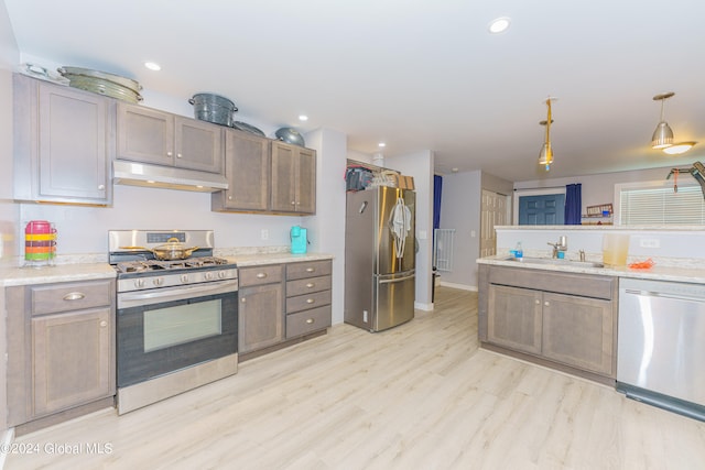 kitchen with sink, appliances with stainless steel finishes, light wood-type flooring, and decorative light fixtures