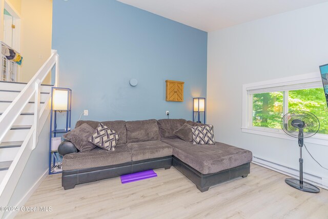 living room with light wood-type flooring and a towering ceiling