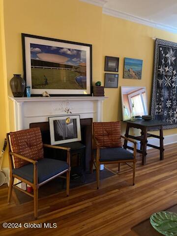 living area with a fireplace, crown molding, and hardwood / wood-style flooring