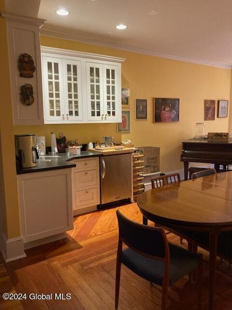 kitchen featuring white cabinets, light parquet flooring, sink, and crown molding