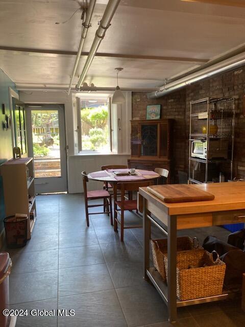 tiled dining space featuring brick wall