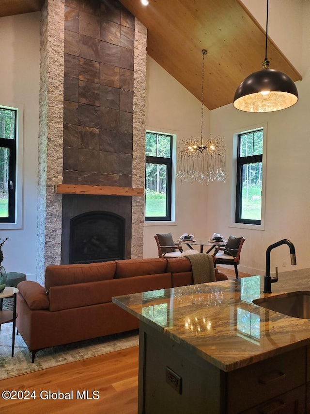 kitchen featuring sink, light hardwood / wood-style flooring, a fireplace, stone countertops, and decorative light fixtures