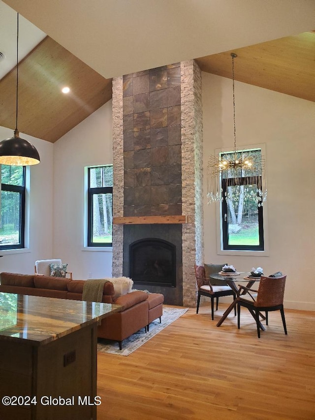 living room with a large fireplace, high vaulted ceiling, hardwood / wood-style floors, and a notable chandelier