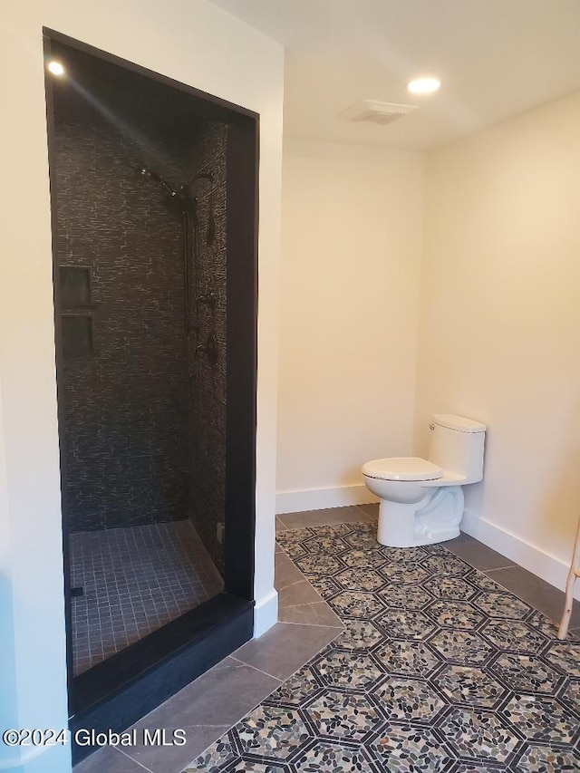 bathroom with tile patterned flooring, tiled shower, and toilet