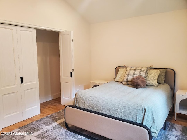 bedroom with vaulted ceiling, wood-type flooring, and a closet