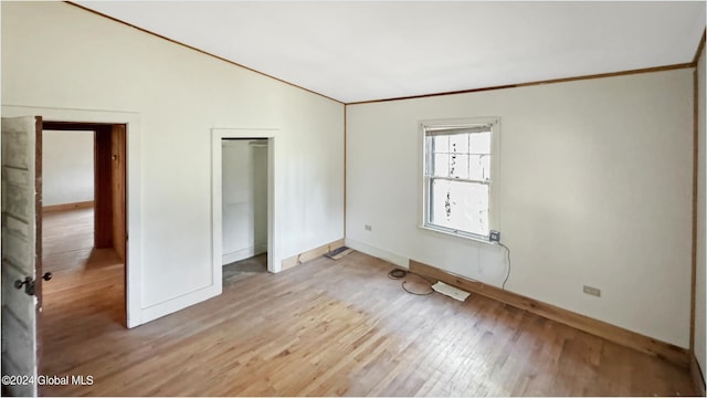 unfurnished bedroom featuring a closet, hardwood / wood-style flooring, and crown molding