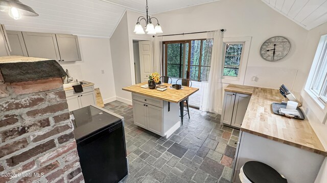 67 Adams Ln, Schroon, NY 12870 - kitchen with butcher block counters, vaulted ceiling, a chandelier, pendant lighting, and a sink