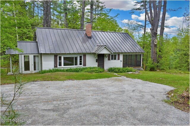 67 Adams Ln, Schroon, NY 12870 - view of front of home featuring a standing seam roof, a chimney, a sunroom, metal roof, and a front lawn