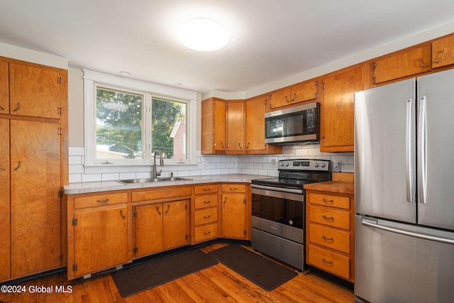 kitchen with stainless steel appliances, sink, dark wood-type flooring, and backsplash