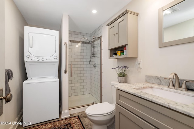 bathroom featuring stacked washer / dryer, vanity, an enclosed shower, and toilet