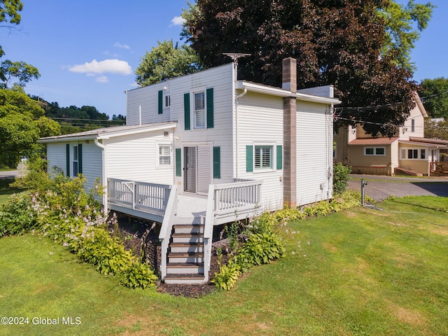 back of property featuring a wooden deck and a yard