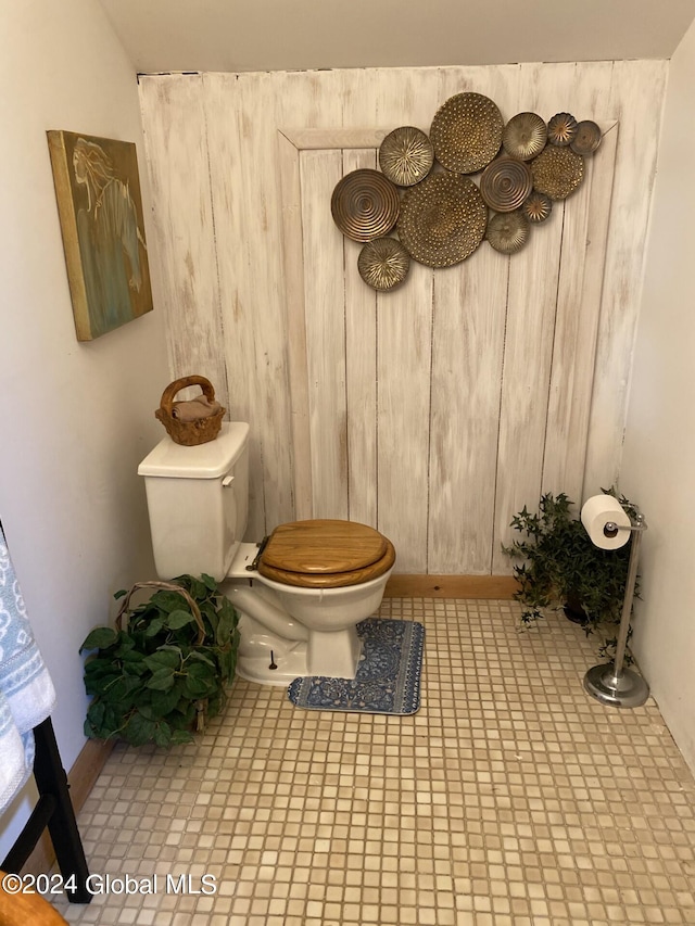 bathroom featuring tile patterned flooring, toilet, and wooden walls