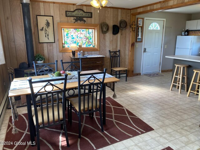 dining room featuring crown molding, ceiling fan, and wooden walls