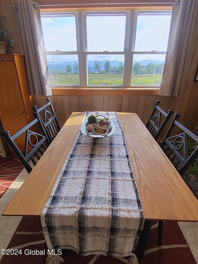 dining space with tile patterned floors and wooden walls