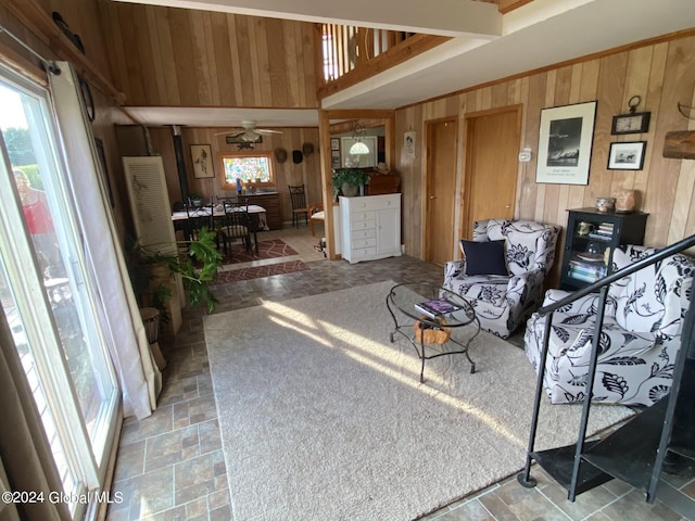 living room with ceiling fan and wood walls