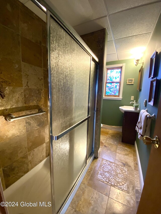 bathroom with vanity, a drop ceiling, and a shower with shower door