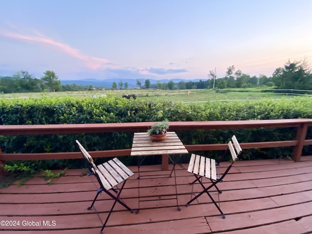 deck at dusk featuring a mountain view and a rural view