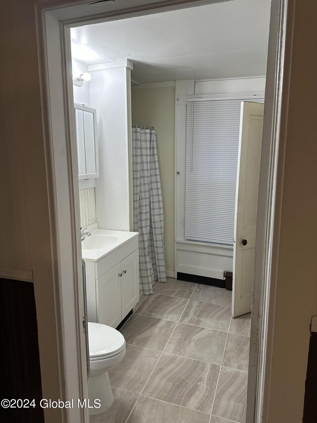 bathroom with tile patterned floors, vanity, toilet, and walk in shower