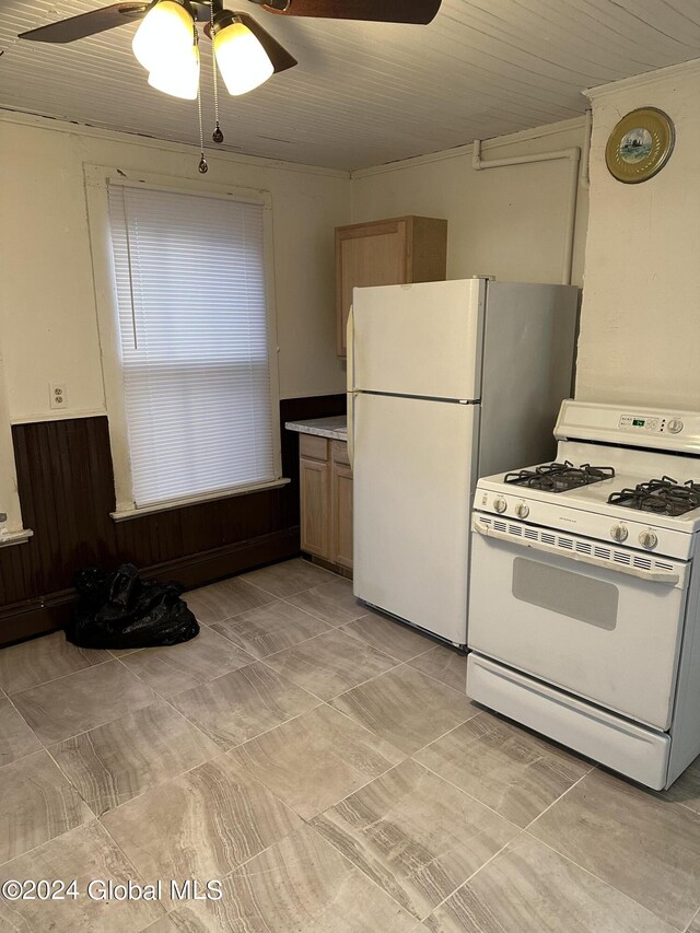 kitchen with ceiling fan, wooden walls, white appliances, and ornamental molding