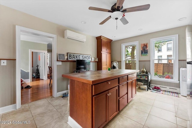 kitchen featuring light tile patterned flooring, a wall unit AC, ceiling fan, and a center island