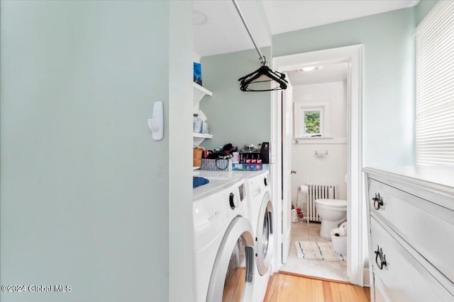 clothes washing area featuring light hardwood / wood-style floors, washer and dryer, and radiator