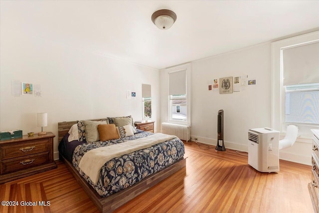 bedroom featuring radiator heating unit and light hardwood / wood-style flooring