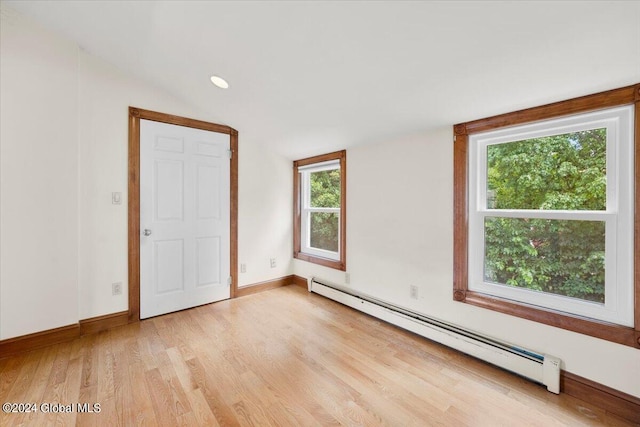 unfurnished bedroom featuring light wood-type flooring and a baseboard heating unit