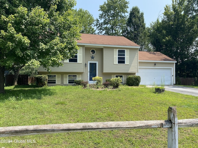 raised ranch featuring a garage, fence, and a front yard