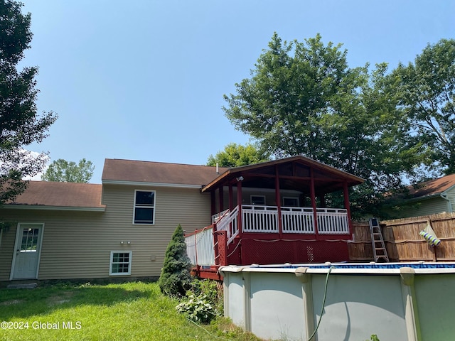 back of house with a lawn and a fenced in pool