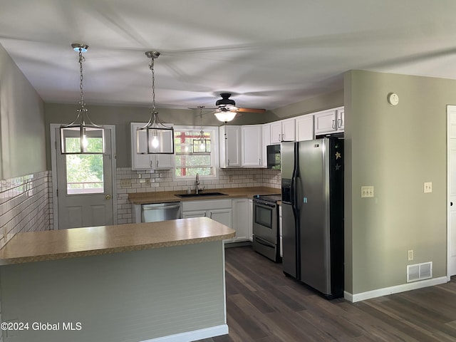 kitchen with dark wood-style flooring, stainless steel appliances, white cabinetry, pendant lighting, and a sink