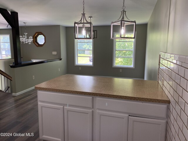 kitchen with dark wood-type flooring, a chandelier, tasteful backsplash, and decorative light fixtures