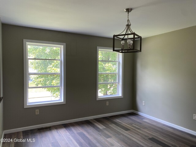 spare room featuring plenty of natural light, dark hardwood / wood-style flooring, and a notable chandelier