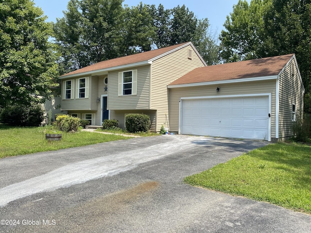 raised ranch featuring a garage, a front yard, and driveway