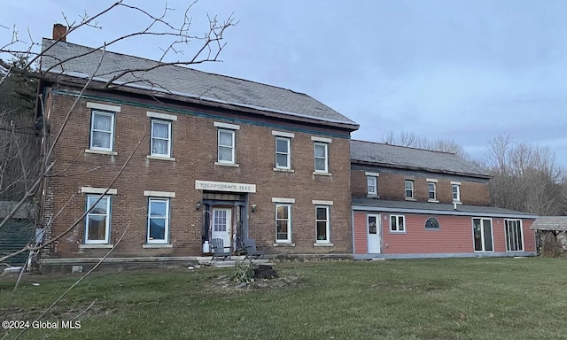 view of front of house featuring entry steps, brick siding, a chimney, and a front lawn