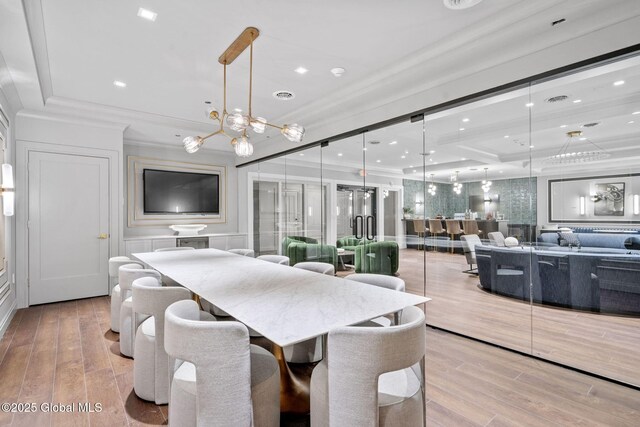 dining room with an inviting chandelier, crown molding, recessed lighting, and wood finished floors