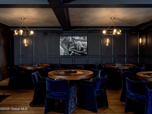 interior space featuring beam ceiling, a decorative wall, wood finished floors, and coffered ceiling