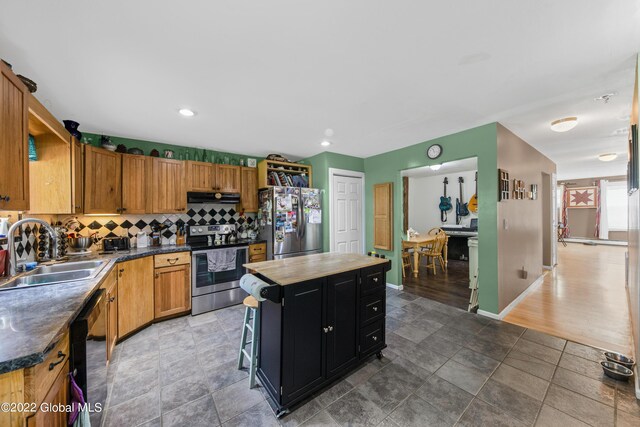 kitchen featuring a center island, backsplash, appliances with stainless steel finishes, hardwood / wood-style flooring, and sink