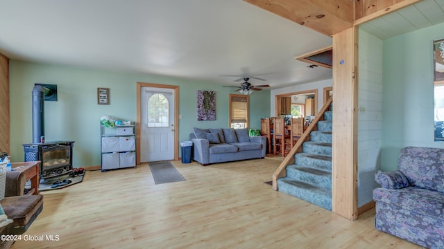 living room featuring a wood stove, ceiling fan, and light wood-type flooring