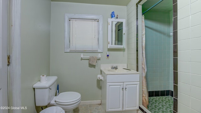 bathroom with tiled shower, tile patterned flooring, toilet, and vanity