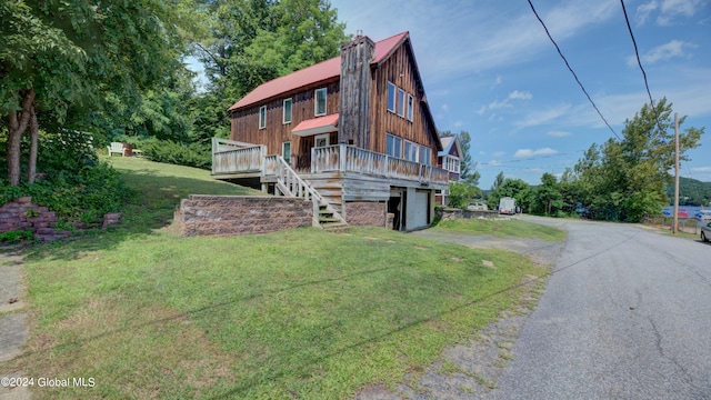 exterior space featuring a garage, a deck, and a front lawn