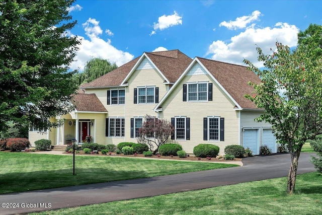 view of front of house featuring a garage, a front yard, driveway, and a shingled roof