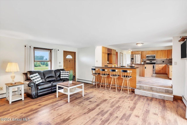 living room with a baseboard heating unit and light hardwood / wood-style floors