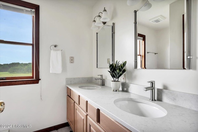 bathroom with dual vanity and a healthy amount of sunlight