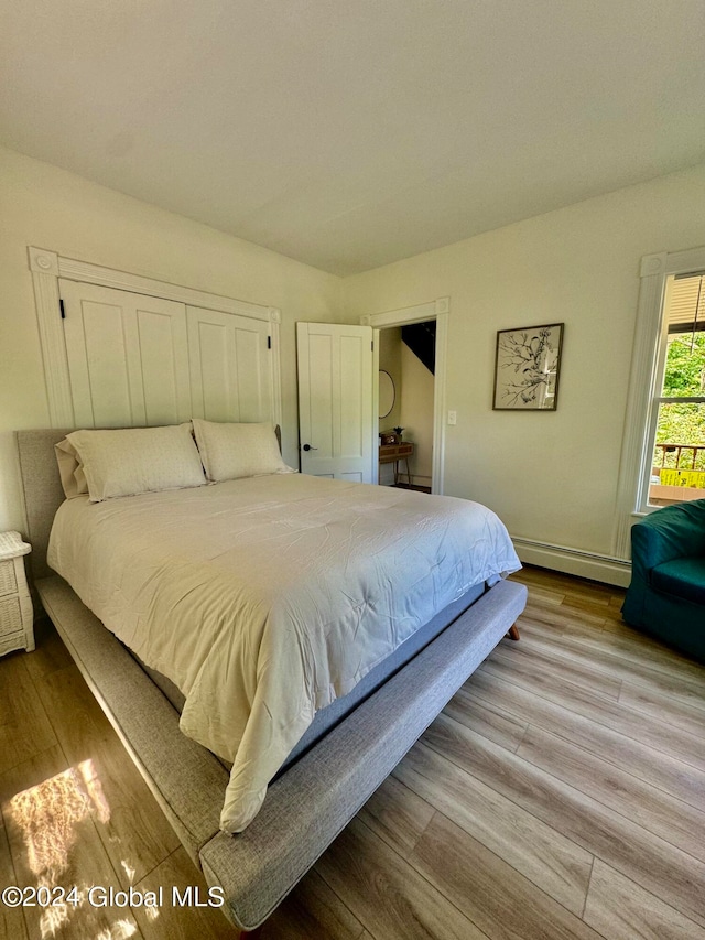 bedroom with light hardwood / wood-style flooring and a baseboard radiator