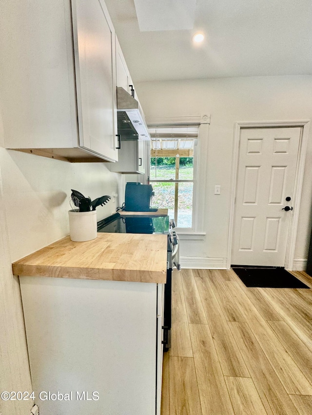 kitchen with white cabinets, range, light hardwood / wood-style flooring, and butcher block counters