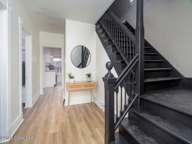 staircase with a baseboard heating unit and hardwood / wood-style flooring