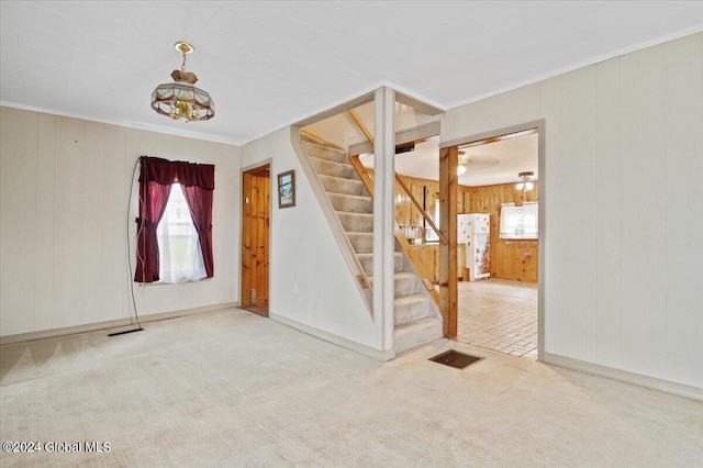 tiled foyer entrance featuring ornamental molding, a notable chandelier, and wooden walls