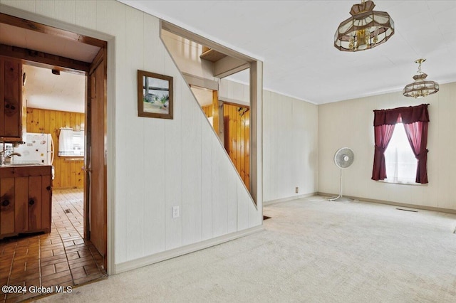 interior space with a notable chandelier, wooden walls, and sink