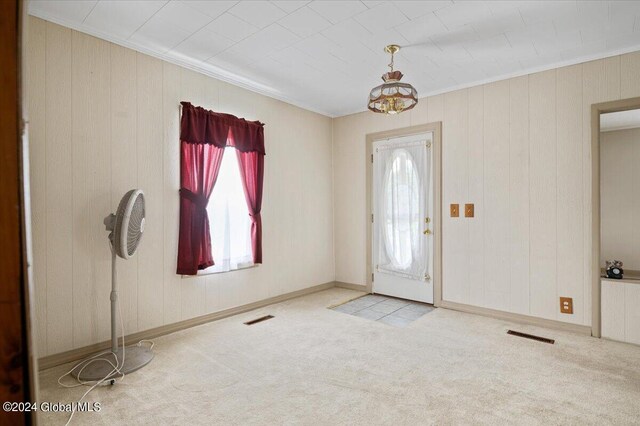 foyer entrance with light colored carpet and ornamental molding